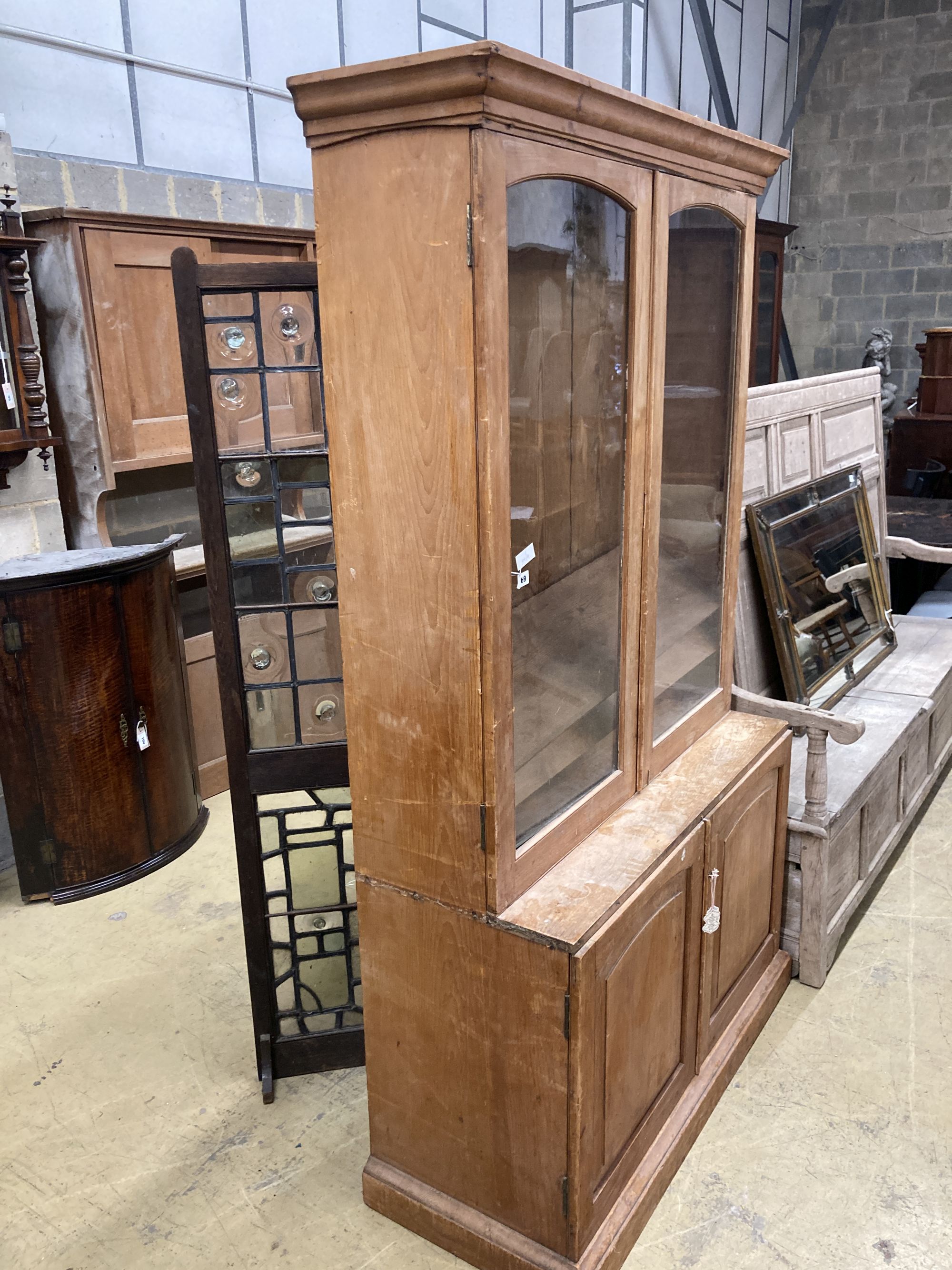 A glazed pine bookcase / cupboard, width 106cm, depth 46cm, height 196cm